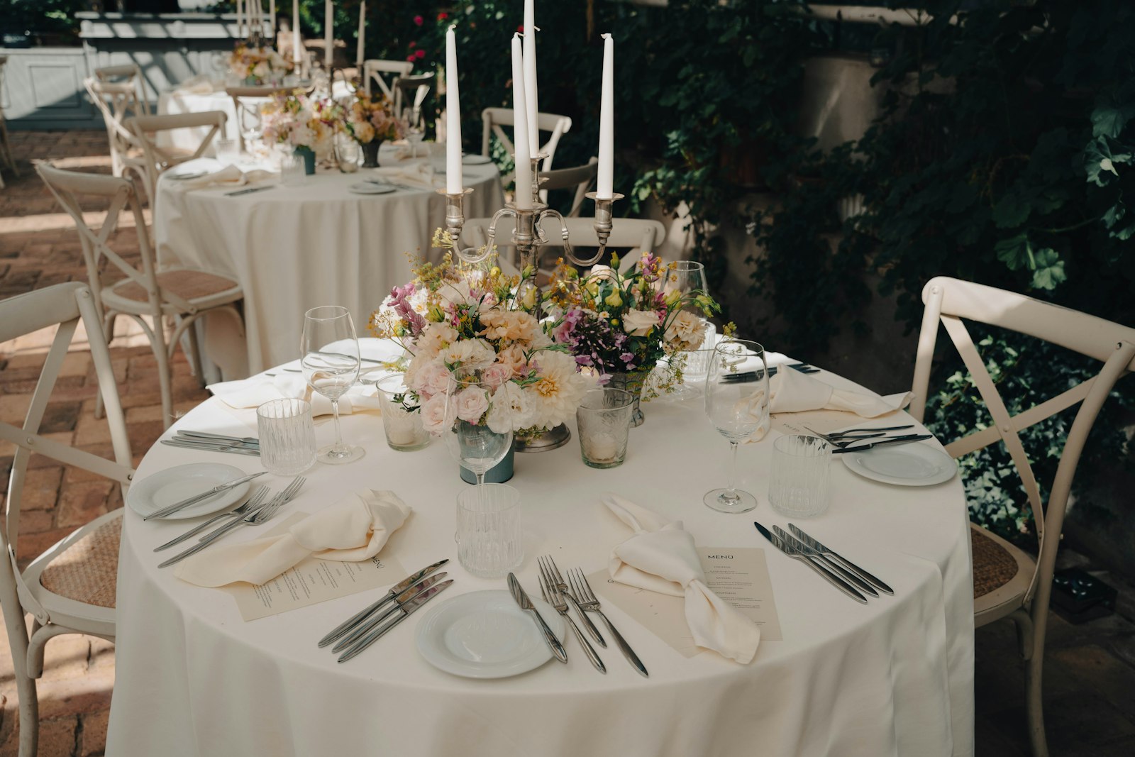 Mesa redonda con mantel blanco, copas y flores